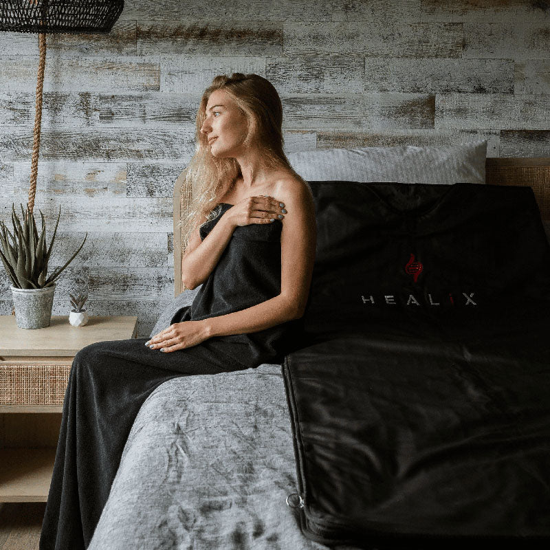 HEALiX-Z Sauna Blanket on a bed, showcasing its sleek, modern design in black with subtle logo branding