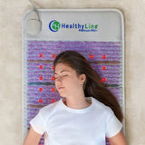 A person relaxing on the Healthy Line Platinum PEMF Mat™ 7224 on a bed, illustrating its intended use for therapy.