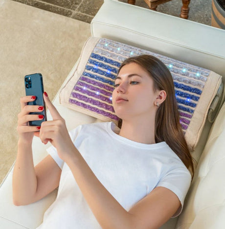 In-Use Image: "Person comfortably using the HealthyLine Rainbow Chakra Pillow while relaxing on a couch, benefiting from the heat and gemstone therapy.