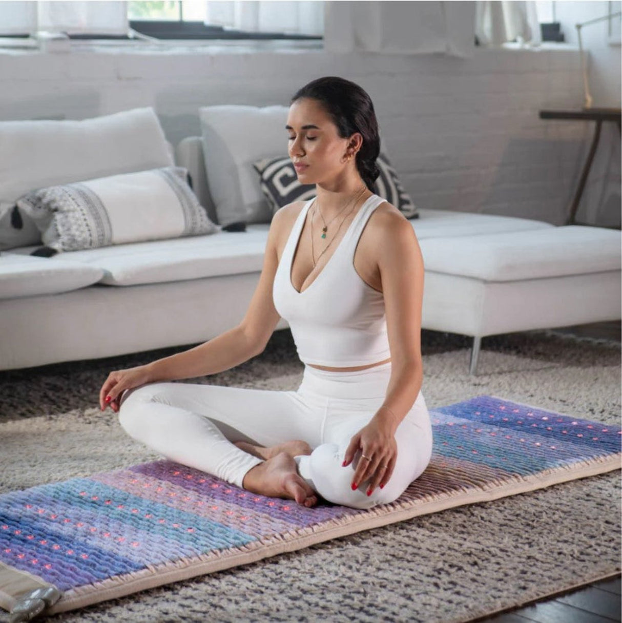 An individual seated in a meditative pose on the Rainbow Chakra Mat™, emphasizing mindfulness and chakra alignment.